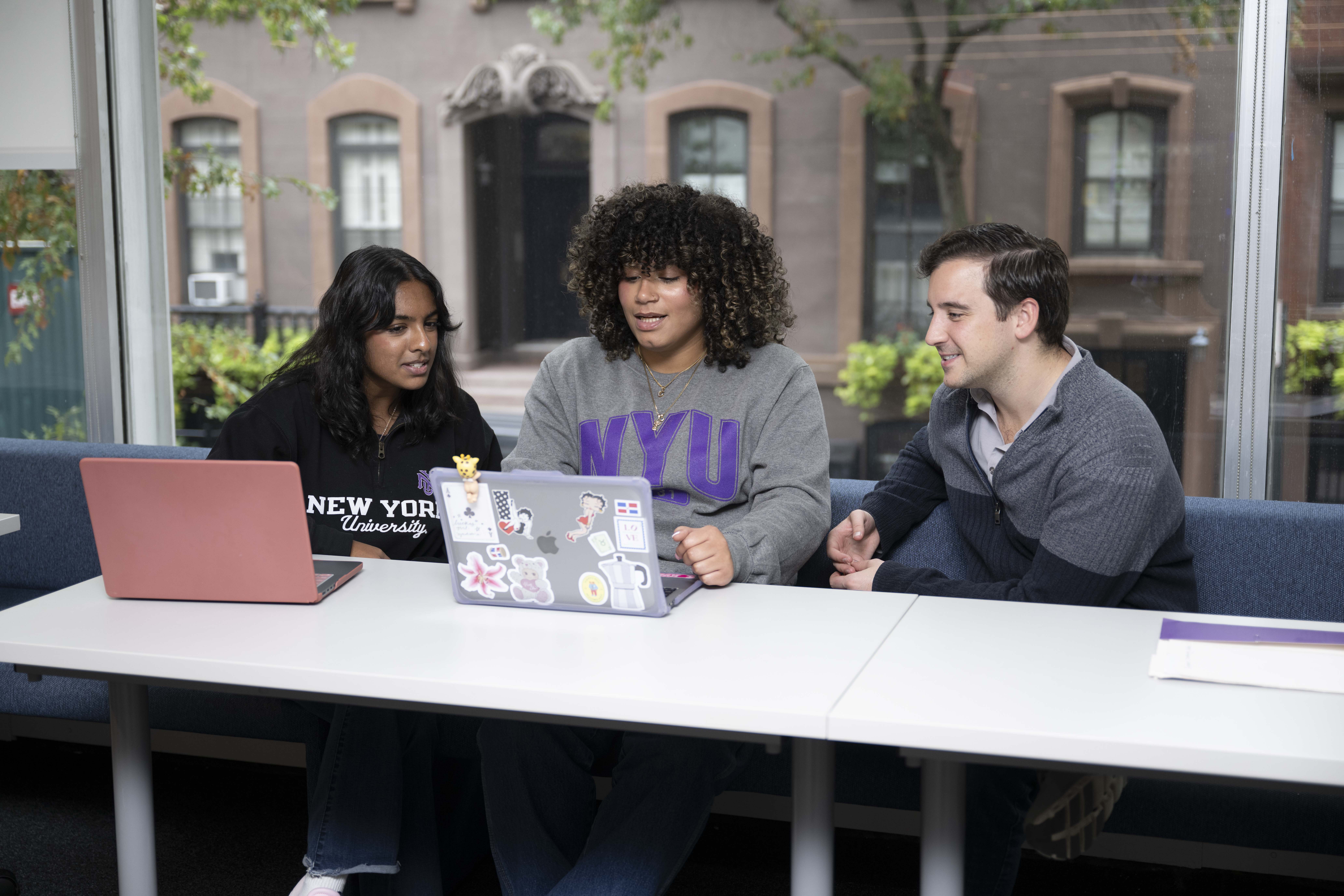 3 students sitting at a table on laptops